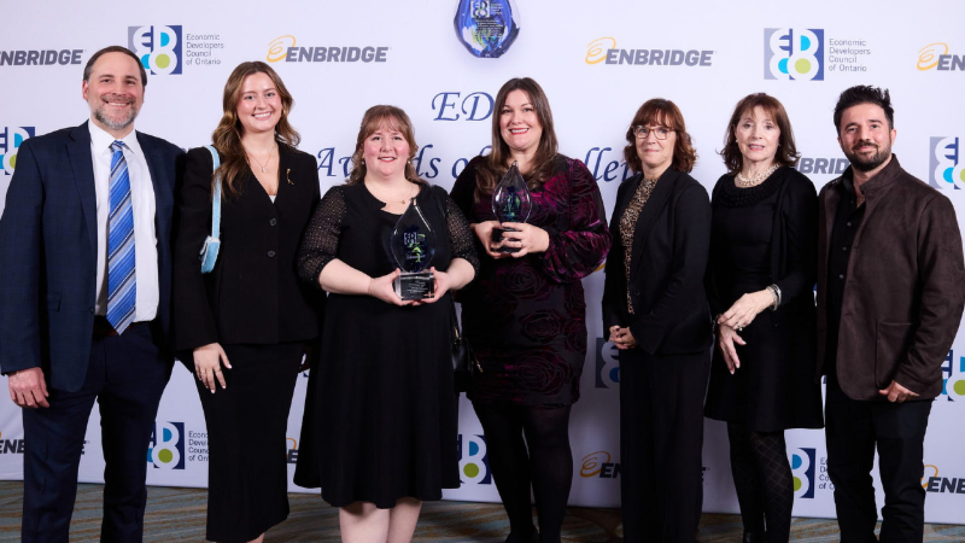 group of men and women standing together showing of the award they received