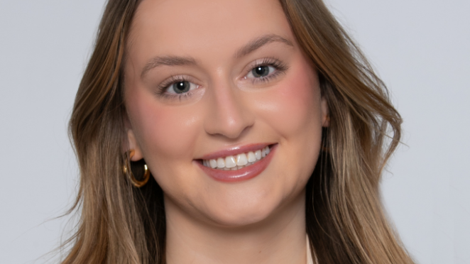  Amber Elliott, a woman with light brown hair smiling in front of a grey background