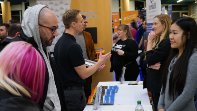 a group of people standing around a booth at a trade show