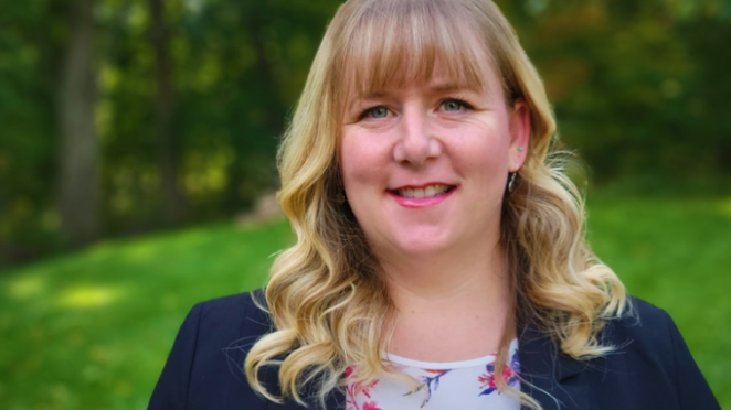 a woman with blond hair wearing a navy blazer and floral shirt