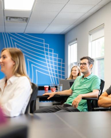 Entrepreneurs sitting at tables listening to a speaker 